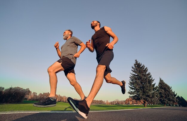 Dwóch szczęśliwych sportowców biegających po alejce