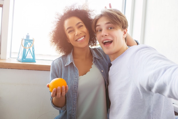 Dwóch szczęśliwych studentów bierze selfie. Dziewczyna trzyma pomarańczowe i uśmiechnięte