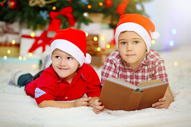Dwóch uroczych małych braci, czytanie książki na powierzchni dekoracji świątecznych