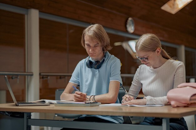 Dwóch utalentowanych studentów pracujących razem nad projektem uniwersyteckim siedzi w bibliotece