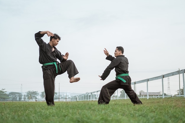 Dwóch wojowników w mundurze pencak silat pozuje z pozycjami