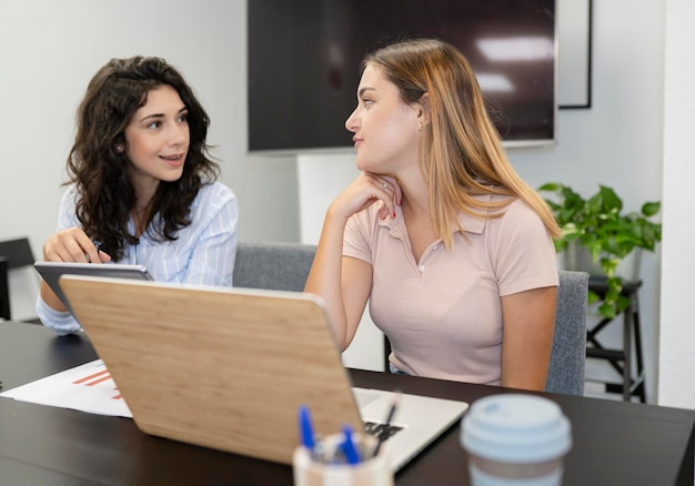 Dwóch współpracowników w biurze coworkingowym rozmawiających przy komputerze skupia się na blond kobiecie