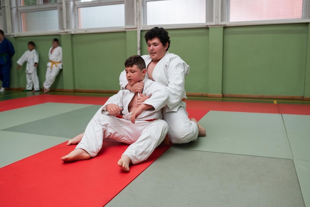 Dwóch zawodników judo pokazujących umiejętności techniczne podczas treningu sztuk walki w klubie walki Dwóch wysportowanych mężczyzn w umundurowanej walce trening karate koncepcja zawodów sportowców Selektywne skupienie