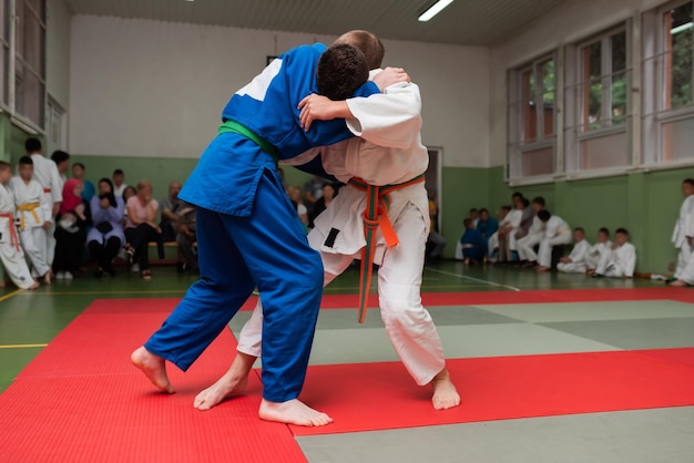 Dwóch zawodników judo pokazujących umiejętności techniczne podczas treningu sztuk walki w klubie walki Dwóch wysportowanych mężczyzn w umundurowanej walce trening karate koncepcja zawodów sportowców Selektywne skupienie