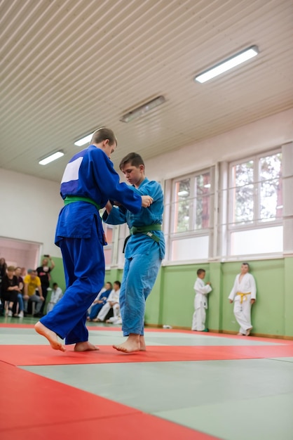 Dwóch zawodników judo pokazujących umiejętności techniczne podczas treningu sztuk walki w klubie walki Dwóch wysportowanych mężczyzn w umundurowanej walce trening karate koncepcja zawodów sportowców Selektywne skupienie