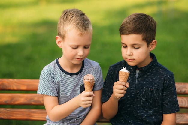 Dwoje Dzieci Bawi Się W Parku. Dwóch Pięknych Chłopców W Koszulkach I Szortach Bawi Się Z Uśmiechem