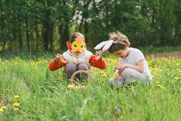 Dwoje dzieci poluje na jaja wielkanocne w ogrodzie wiosennym.