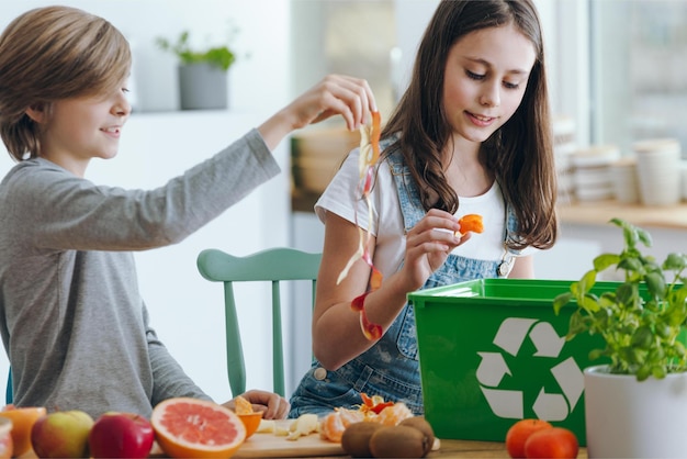 Dwoje Dzieci Sortuje żywność W Koszu Do Recyklingu.