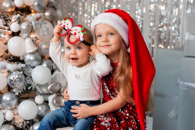 Dwoje dzieci z prezentami w pobliżu strefy zdjęć choinki