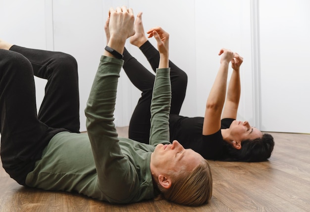 Dwoje ludzi robi ćwiczenia relaksacyjne na podłodze