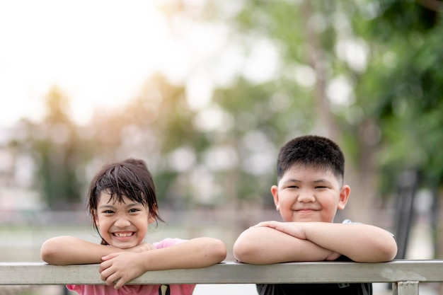 Dwoje małych azjatyckich dzieci, chłopiec i dziewczynka, szczęśliwe i uśmiechnięte w parku