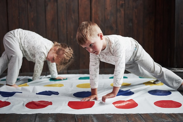 Dwoje szczęśliwych dzieci bawiące się w twister w domu. Brat i siostra bawią się na wakacjach