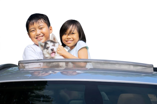 Dwoje szczęśliwych dzieci obejmuje psa na szyberdach samochodu