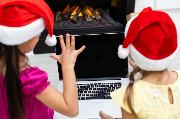 Dwoje uroczych dzieci oglądających laptopa w pokoju pięknie udekorowanym na Boże Narodzenie