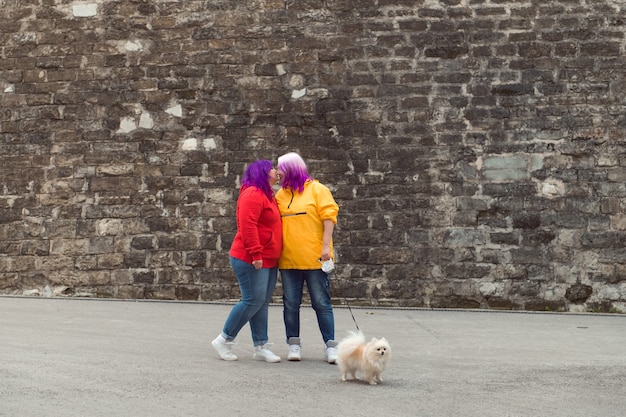 Dwukolorowe Włosy Lesbijek Z Małym Psem Całującym Się Na Tle Kamiennego Muru Ulica Miasta