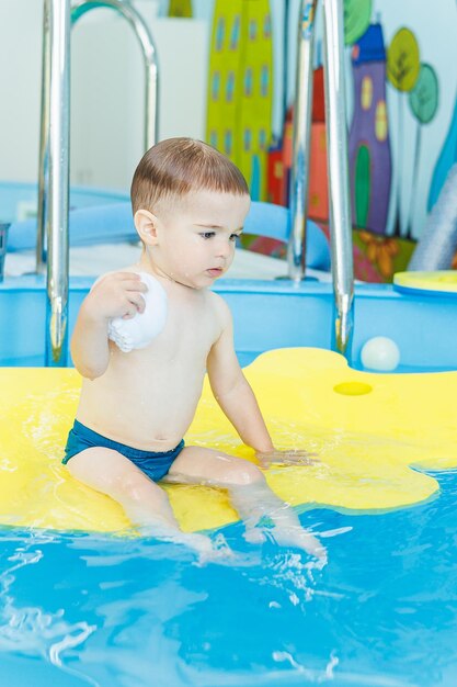 Zdjęcie dwuletni chłopczyk uczy się pływać w basenie lekcje pływania dla małych dzieci szkoła pływania dla dzieci