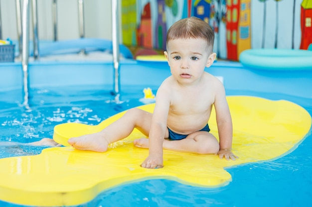 Dwuletni chłopczyk uczy się pływać w basenie Lekcje pływania dla małych dzieci Szkoła pływania dla dzieci