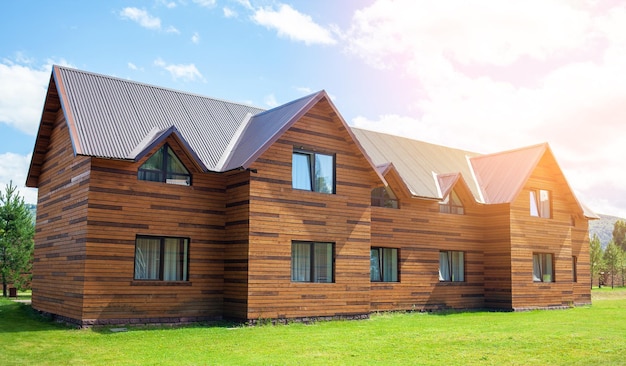 Dwupiętrowy drewniany domek z oknami natury z zielonym trawnikiem. Sprzedaż lub zakup nowych domów.