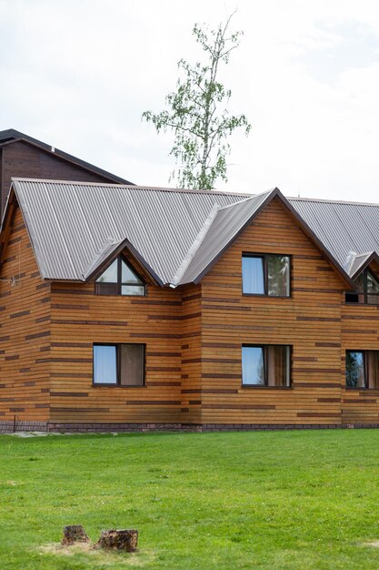 Dwupiętrowy drewniany domek z oknami natury z zielonym trawnikiem