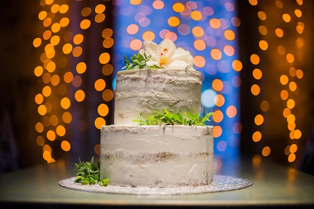 Dwupoziomowy tort weselny z naturalnymi kwiatami na tle bokeh