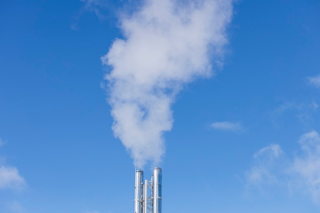 Zdjęcie dym ze srebrnych kominów na tle błękitnego nieba. koncepcja ochrony środowiska. zdjęcie wysokiej jakości