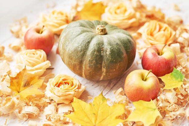 Dynia na jesień tle z jabłkami, kwiatami i liśćmi.