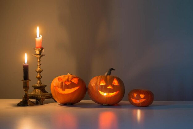 dynie halloween z płonącymi świecami na białym stole