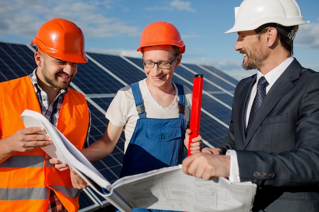 Dyrektor, Brygadzista I Pracownik Przeglądający Rysunki Techniczne Na Stacji Solarnej.