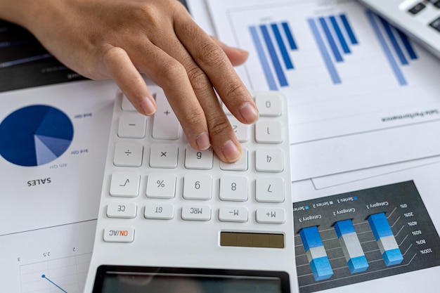 Dyrektor finansowy firmy używa kalkulatora, używa kalkulatora do obliczania liczb w dokumentach finansowych firmy, które pracownicy działu tworzą jako dokumenty na spotkania.