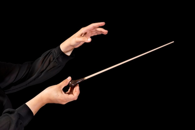 Dyrygentka dyrygująca symfonią z batutą na czarnym tle
