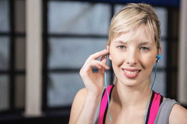 Zdjęcie dysponowana blondynka słucha muzyki na siłowni