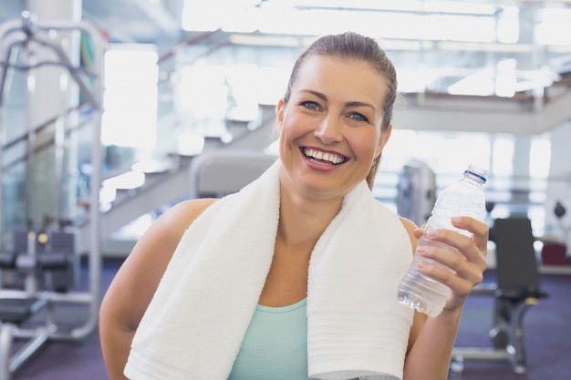 Dysponowana brunetka ono uśmiecha się przy kamerą z ręcznikiem wokoło ramion