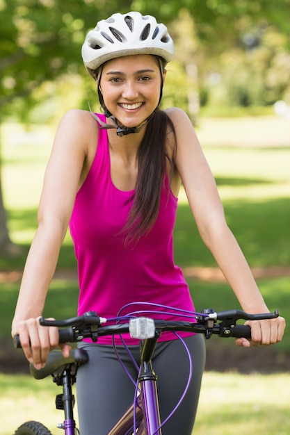 Dysponowana młoda kobieta z hełma jeździeckim bicyklem