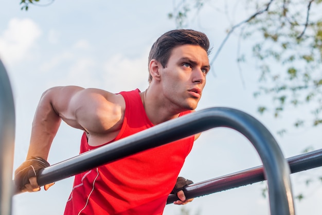Dysponowany mężczyzna robi triceps zamacza na równoległych barach ćwiczy outdoors na parku