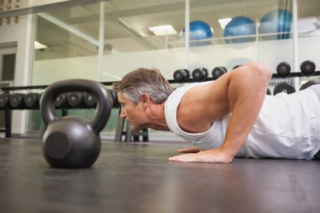 Dysponowany mężczyzna używa kettlebells w jego treningu