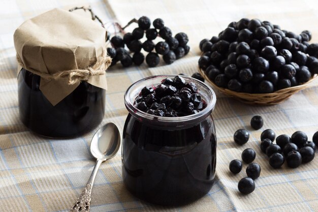 Dżem aroniowy w słoiku i aronia na stole