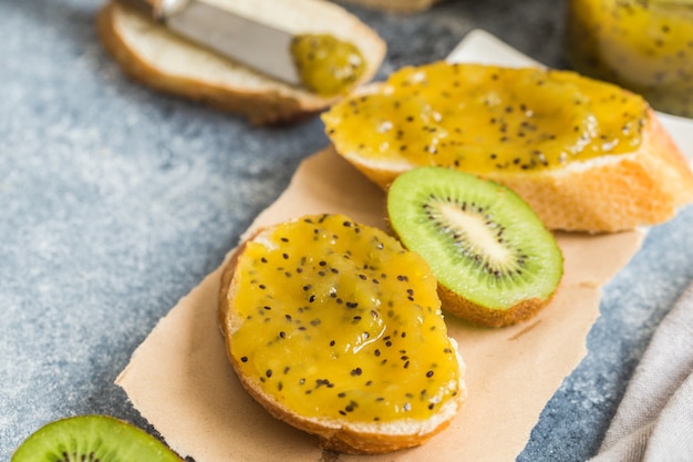 Dżem lub marmolada z kiwi na świeżym pieczywie. śniadanie, tosty z dżemem na szarym tle