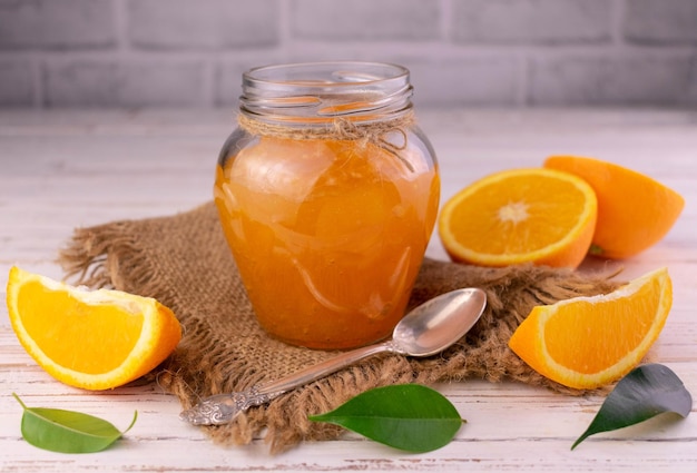 Dżem pomarańczowy w szklanym słoju na białym drewnianym tle
