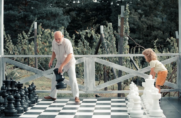 Zdjęcie dziadek i syn grają w szachy na dużej szachownicy weekend z dziadkiem