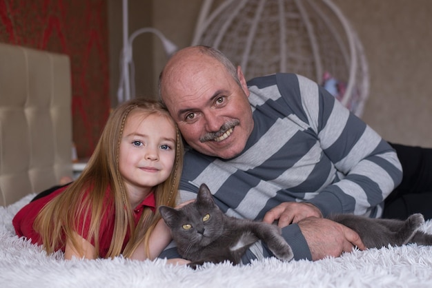 dziadek i wnuczka bawią się razem z kotem