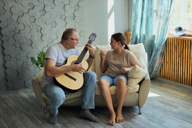 Dziadek i wnuczka śpiewają i grają na gitarze.