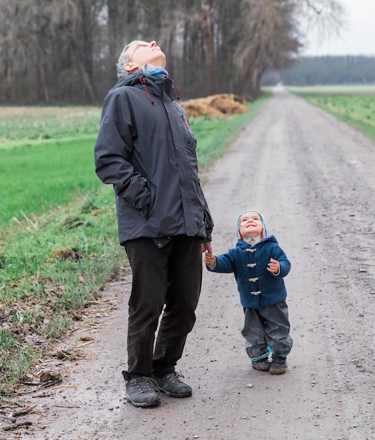 Zdjęcie dziadek i wnuk patrzą w górę, stojąc na brudnej drodze.