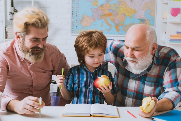 Dziadek ojciec i syn uczą się pisać i czytać dziadek uczy w domu wnuczka klasa m