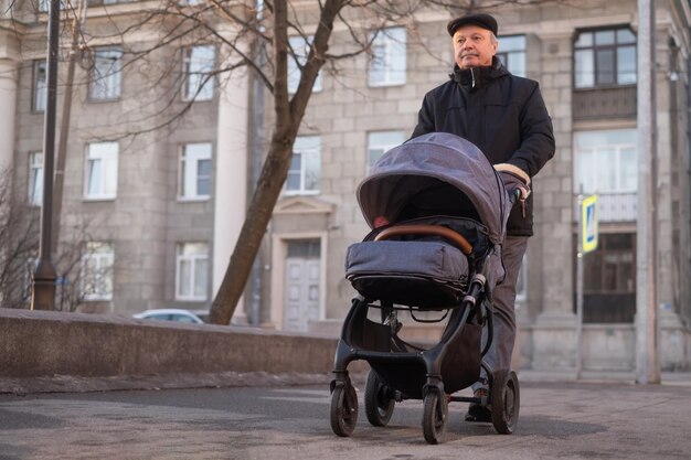 Dziadek spacerujący z wózkiem dziecięcym w śnieżny zimowy dzień