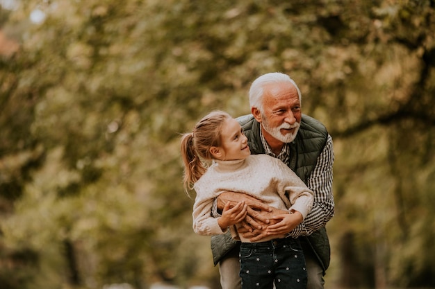 Dziadek spędza czas z wnuczką w parku w jesienny dzień