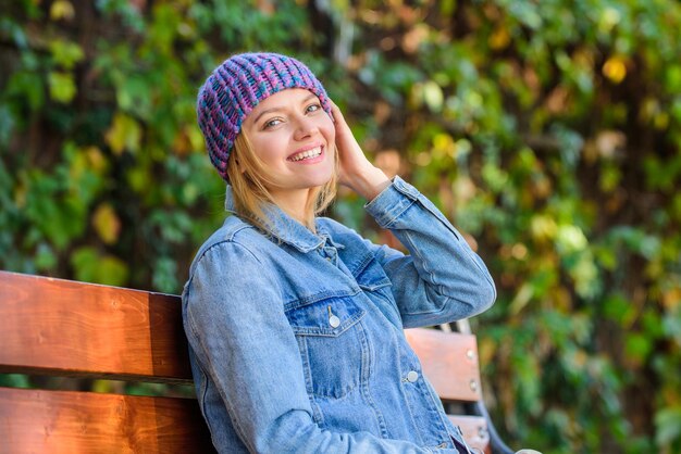 Dzianinowy dodatek na sezon jesienny Jesienny dodatek modowy Poczuj się komfortowo tej jesieni w miękkim i ciepłym stylowym kapeluszu Kobieta siedzi na ławce w parku Natura w tle Dziewczyna nosi dzianinowy kapelusz akcesoria