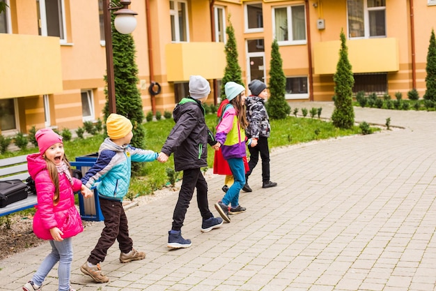 Dzieci bawią się trzymając się za ręce i biegają po szkolnym dziedzińcu