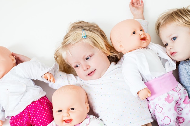 Dzieci bawiące się lalkami. Chłopiec i dziewczynki siedzą na podłodze w przedszkolu i bawią się w rodzinę. Pojęcie ojcostwa