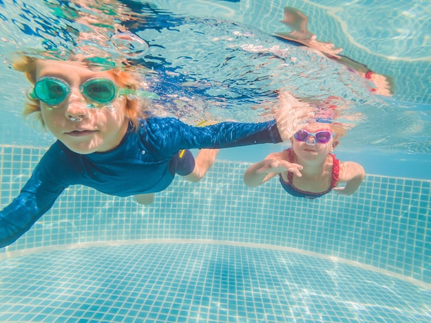 Dzieci bawiące się pod wodą w basenie na letnie wakacje