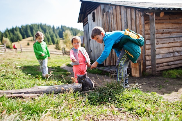 Zdjęcie dzieci bawiące się z kotem w górskiej wiosce.